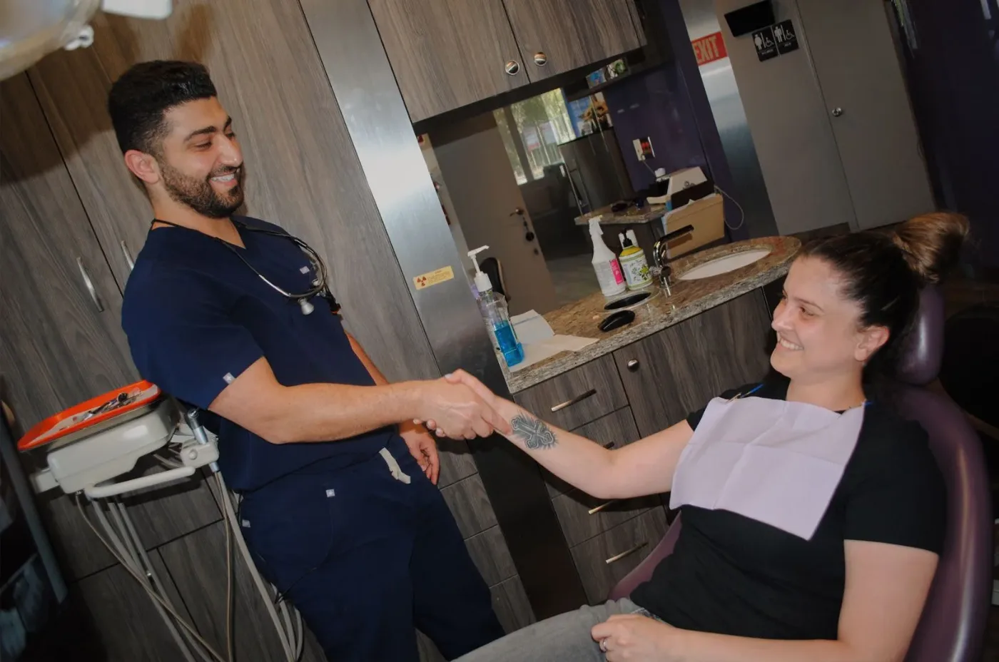 Dentist shaking hands with a smiling patient in the dental chair